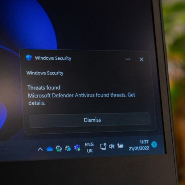 Windows Security alert on a laptop screen: threats found by Microsoft Defender Antivirus, with a Dismiss button nearby.