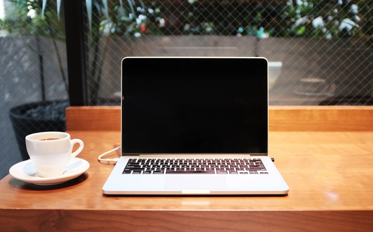 Laptop junto a taza de café en espacio de trabajo — productividad con chips ARM