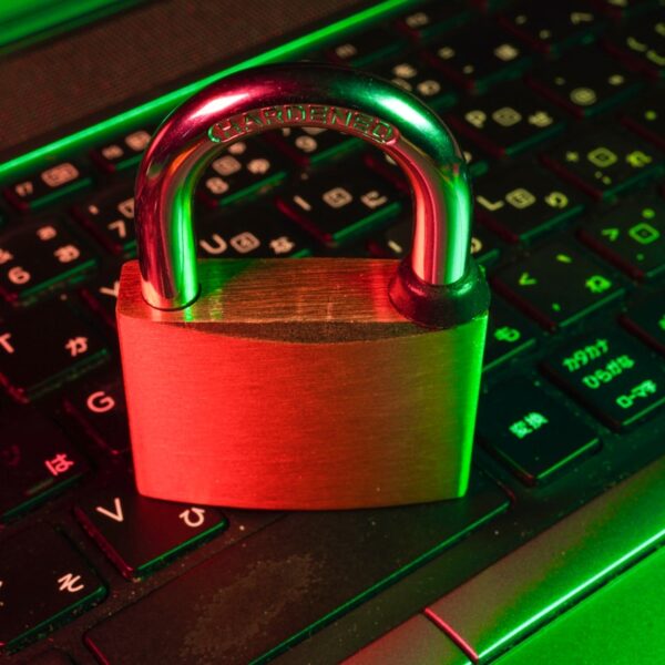 Padlock resting on a laptop keyboard under red and green lighting, symbolizing cybersecurity and data protection
